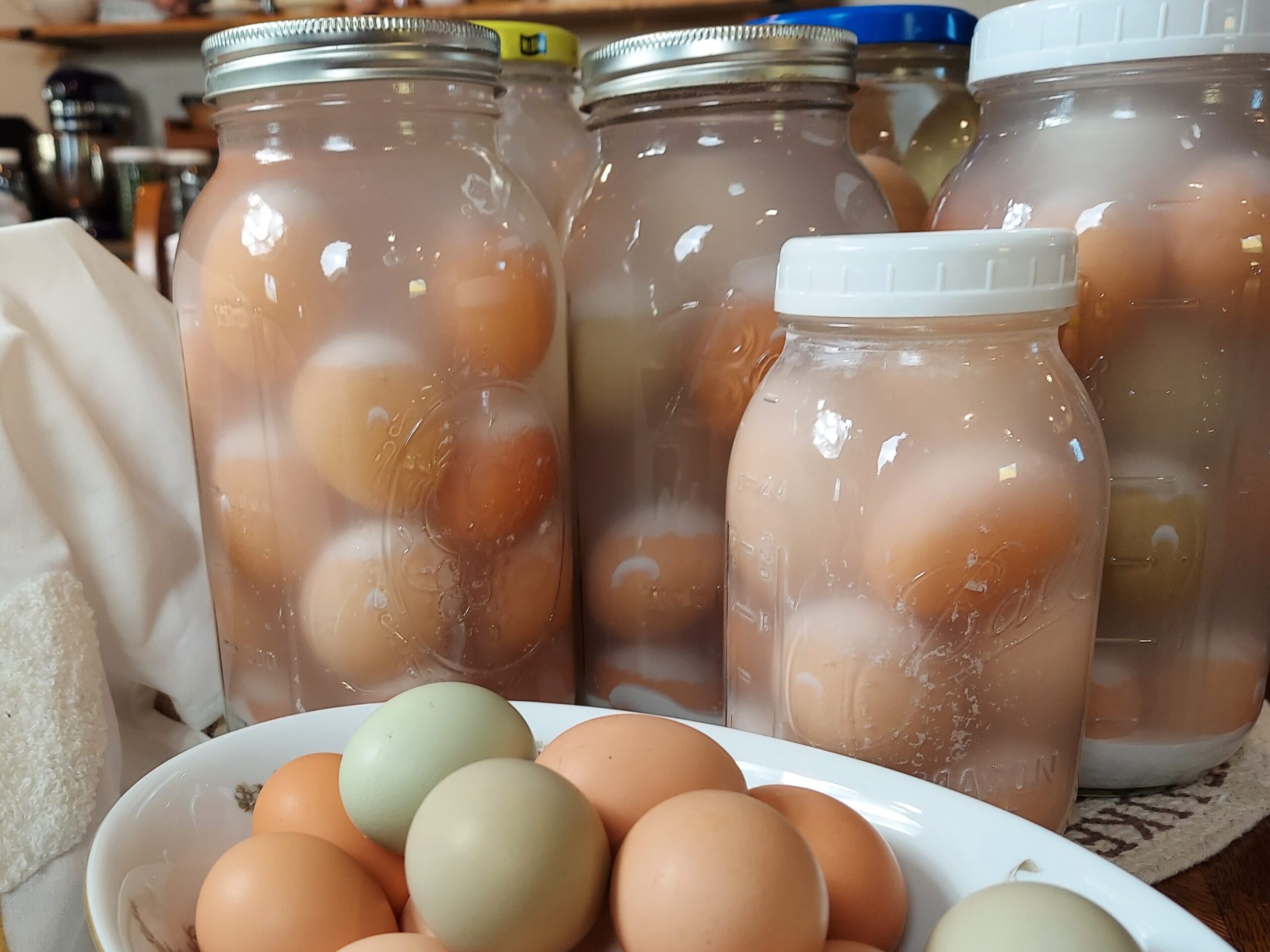 Glass jars with waterglassing eggs, and bowl with farm-fresh eggs.